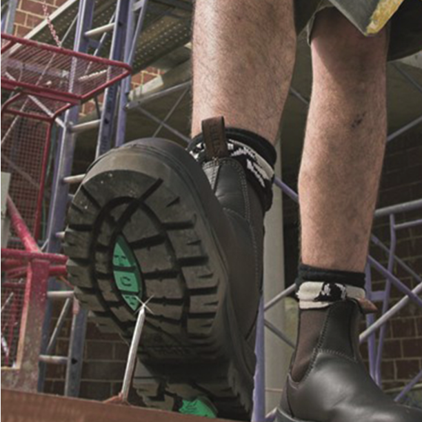 Person wearing black work boots on a construction site