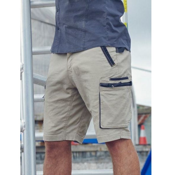Beige cargo shorts with dark trim worn by a person, blurred background