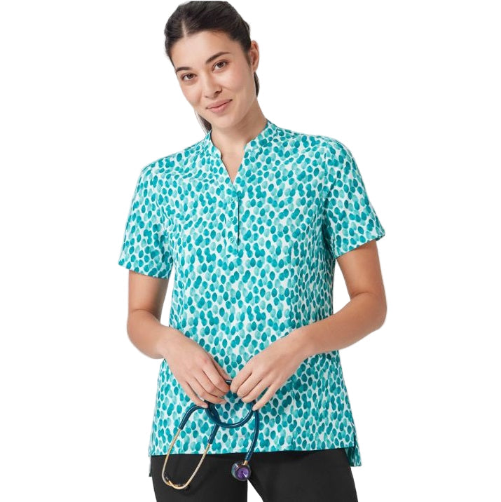 Woman wearing a teal patterned scrub top holding a stethoscope on a white background