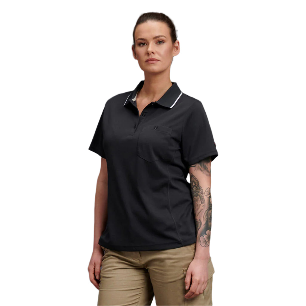 Woman wearing a black polo shirt and beige pants against a gray background