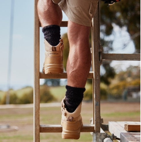 Tradie climbing up ladder with work boots on