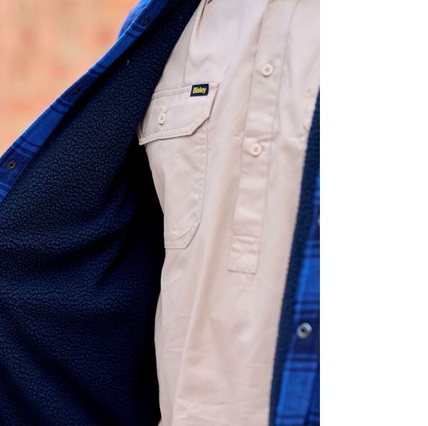 Close-up of a blue fleece jacket and beige shirt with a brand logo.