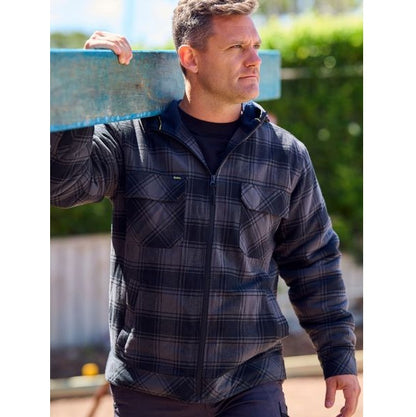 Man wearing a plaid jacket holding a blue object outdoors