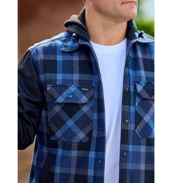 Person wearing a blue plaid jacket over a white shirt with a blurred background