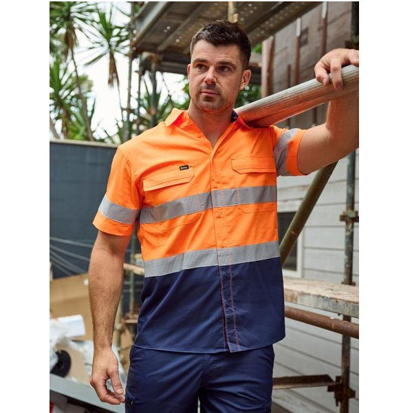Man wearing a high-visibility orange and blue work shirt outdoors.