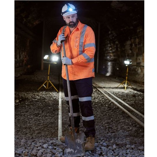 Person in high-visibility safety gear with a shovel in a tunnel setting