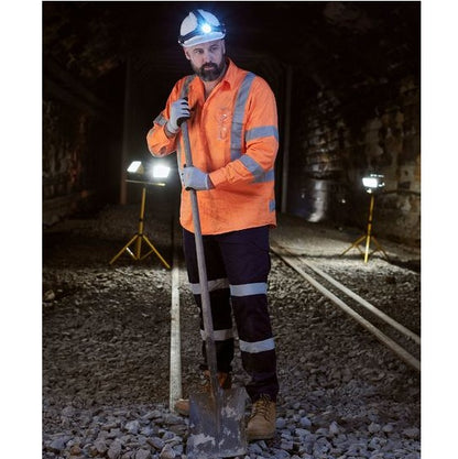 Person in high-visibility safety gear with a shovel in a tunnel setting