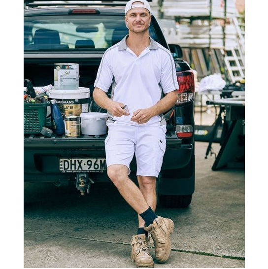 Man in white outfit standing next to a car with tools and equipment in the background