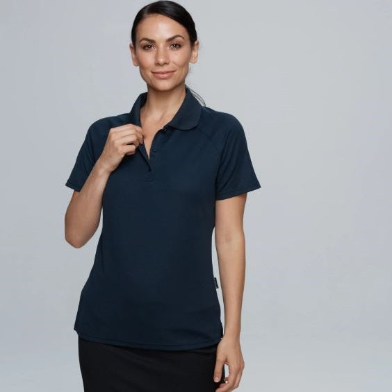 A woman wearing a navy-colored short-sleeved polo shirt with a knitted collar and a 3-button placket.