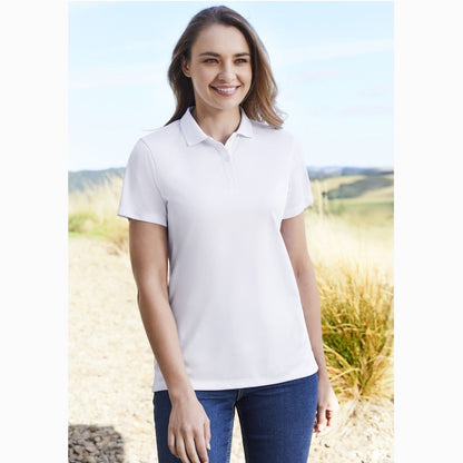 A woman wearing a white short sleeve polo shirt with a collar and pearlized buttons, standing outdoors.