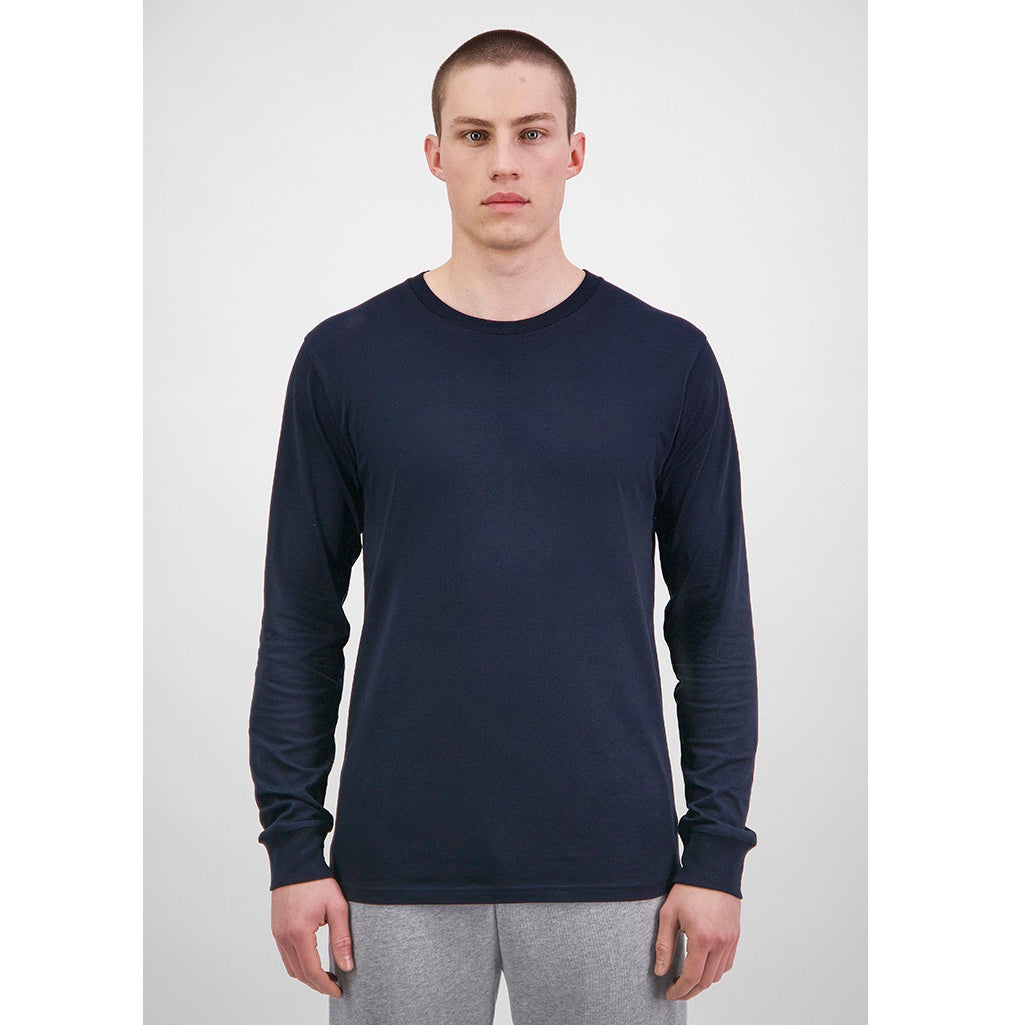 Man wearing a navy long-sleeve shirt and gray pants on a white background