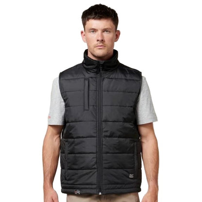 Man wearing a black puffer vest over a gray shirt on a white background