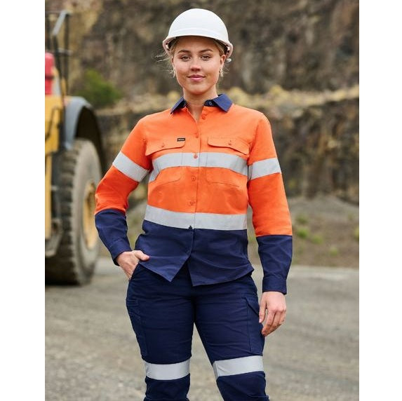 Person wearing an orange and navy work uniform with reflective stripes, standing in front of a blurred background.