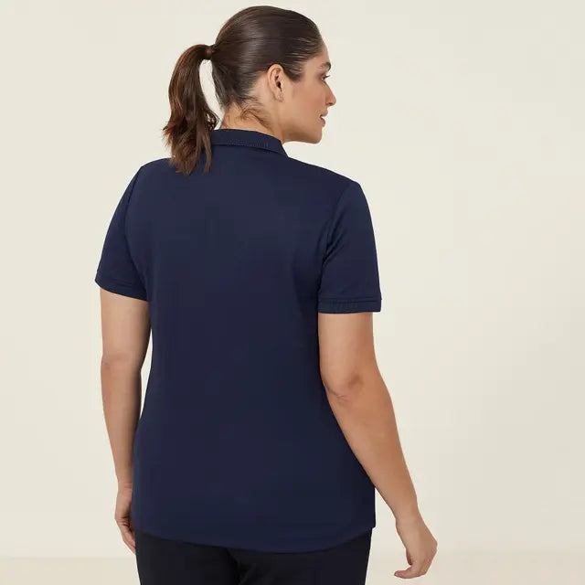 Professional woman wearing an NNT CATU58 navy blue polo shirt against a beige background - Back view