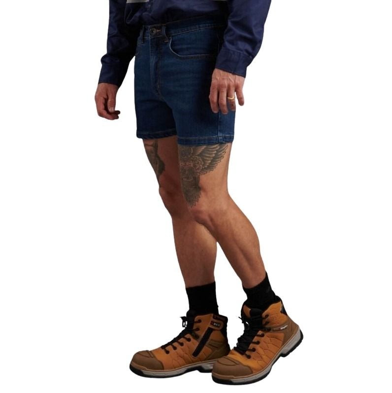 Person wearing blue denim shorts and brown work boots on a white background