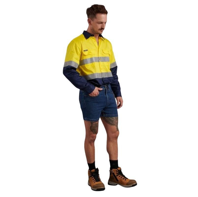 Person wearing a high-visibility yellow and navy work jacket with denim shorts on a white background