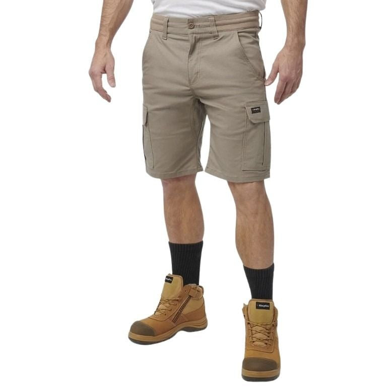 Person wearing beige cargo shorts and brown work boots on a white background