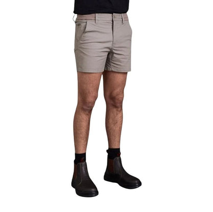 Person wearing beige shorts and black Chelsea boots on a white background