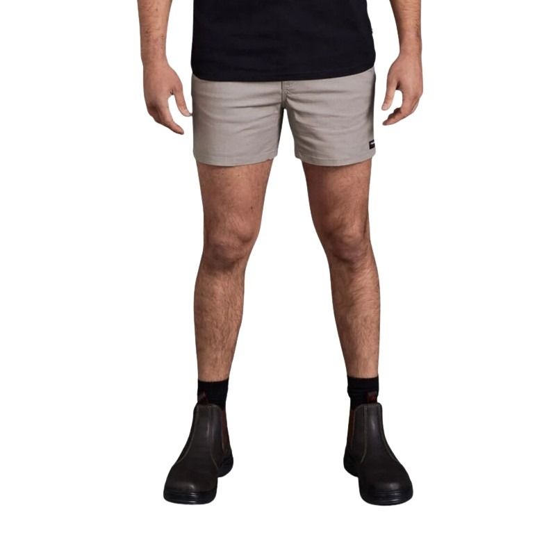 Person wearing beige shorts and black boots on a white background