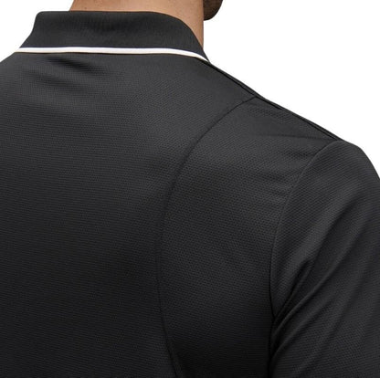 man wearing a black polo with white edge on collar one pocket and button down on white background.