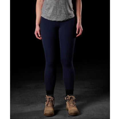 Person wearing navy leggings and brown boots on a dark background