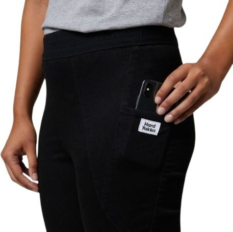 Person wearing black pants with a visible brand label, holding a phone.